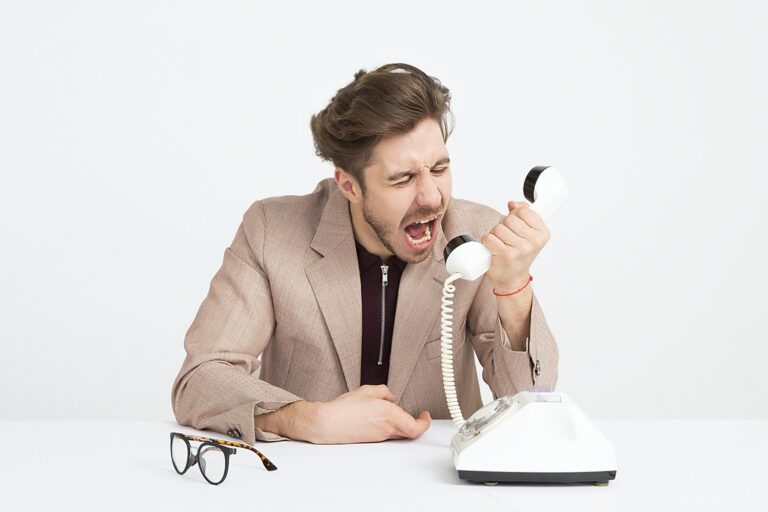 image of a man yelling at a phone because he is frustrated with an automated answering service